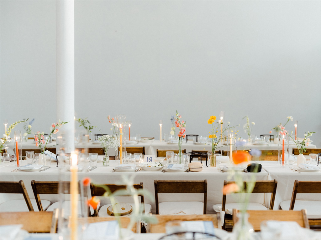 Farm tables sunset colors taper candles and bud vases sound river studio reception flowers low waste sustainable